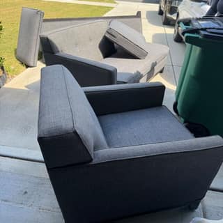 Grey armchair and sofa set out in a driveway for pickup