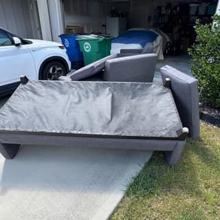 Grey sofa sections staged beside the bins for removal