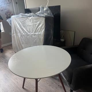 Round table and a wrapped appliance waiting for removal in an apartment