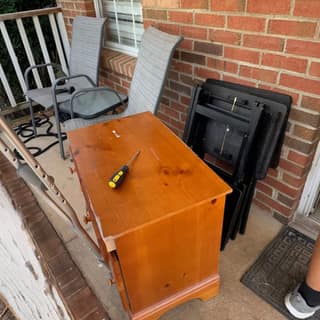 Wooden nightstand and folding chairs on a porch for haul-away