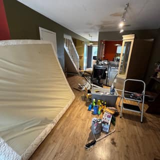 Mattress and cleaning supplies in a living room before a cleanout