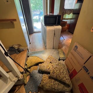 Boxes, carpet padding and furniture in a room before a cleanout