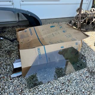 Boxed item and a glass panel on gravel, ready for pickup